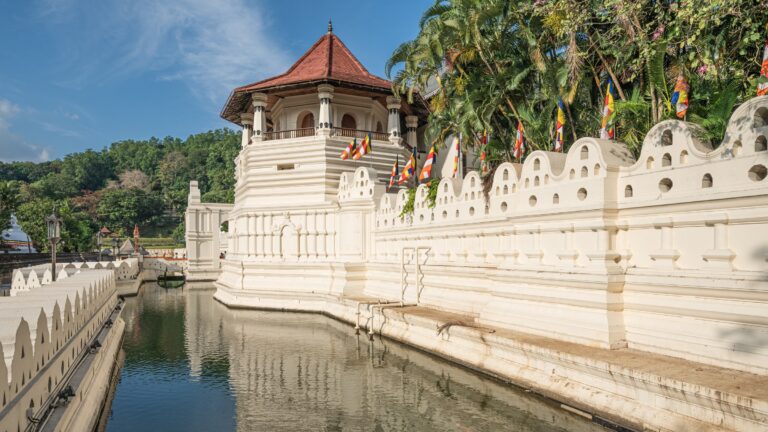Temple of the Sacred Tooth Relic in Kandy with its octagonal tower, moat and white walls under a blue sky